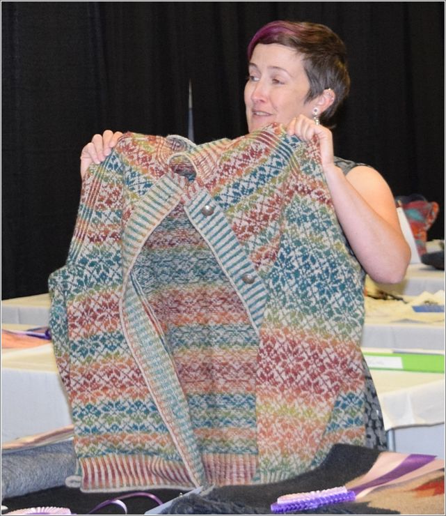 While fiber Arts judge Kira Delaney holds up Deborah Bedes Fair Isle sweater, she explains what she likes about this garment to the audience. Photo: Peggy Lundquist.